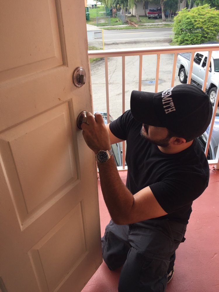 A locksmith working on a deadbolt on a painted front door