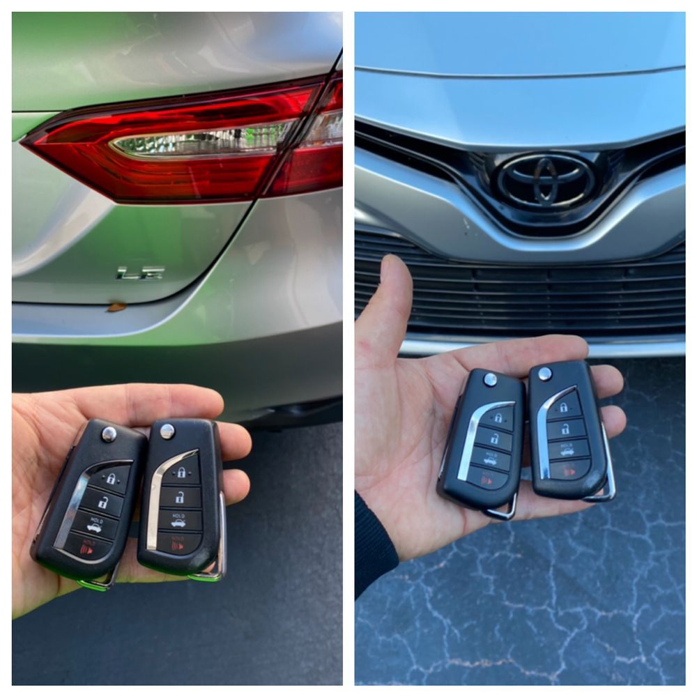 A Toyota flip key and a Toyota smart key held in front of a silver Toyota